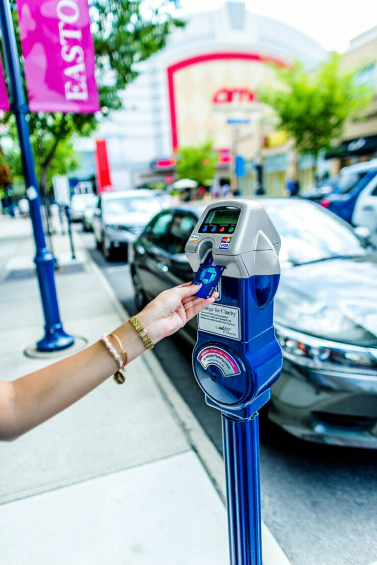 A woman's arm shown putting a credit card into a parking meter for Change for Charity at Easton Town Center.