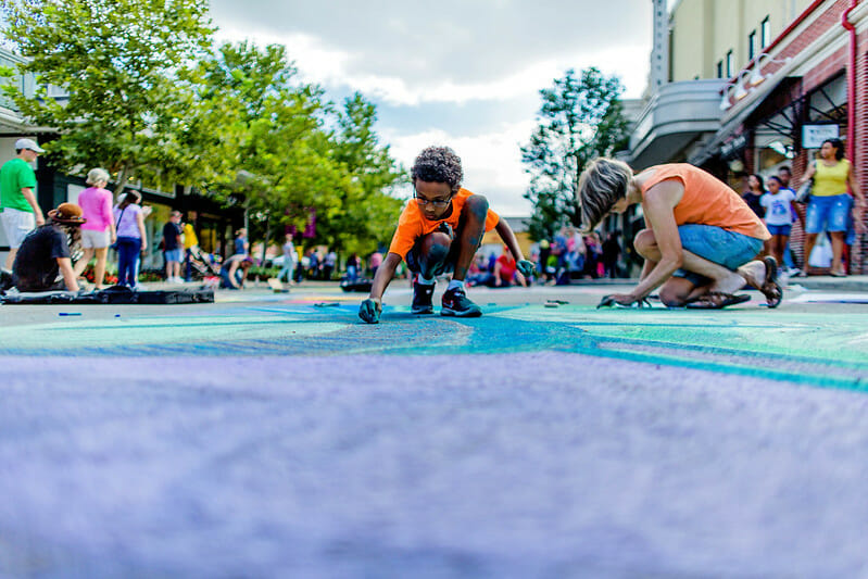 A boy and a woman drawing on the ground with chalk at Easton.