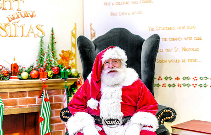 Santa sitting in a chair with holiday decorations around him