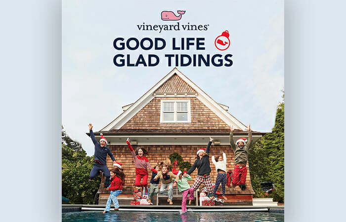 a group of adults and kids jumping into a pool while wearing santa hats and vineyard vines clothing with promotional copy that reads GOOD LIFE GLAD TIDING and the vineyard vines logo