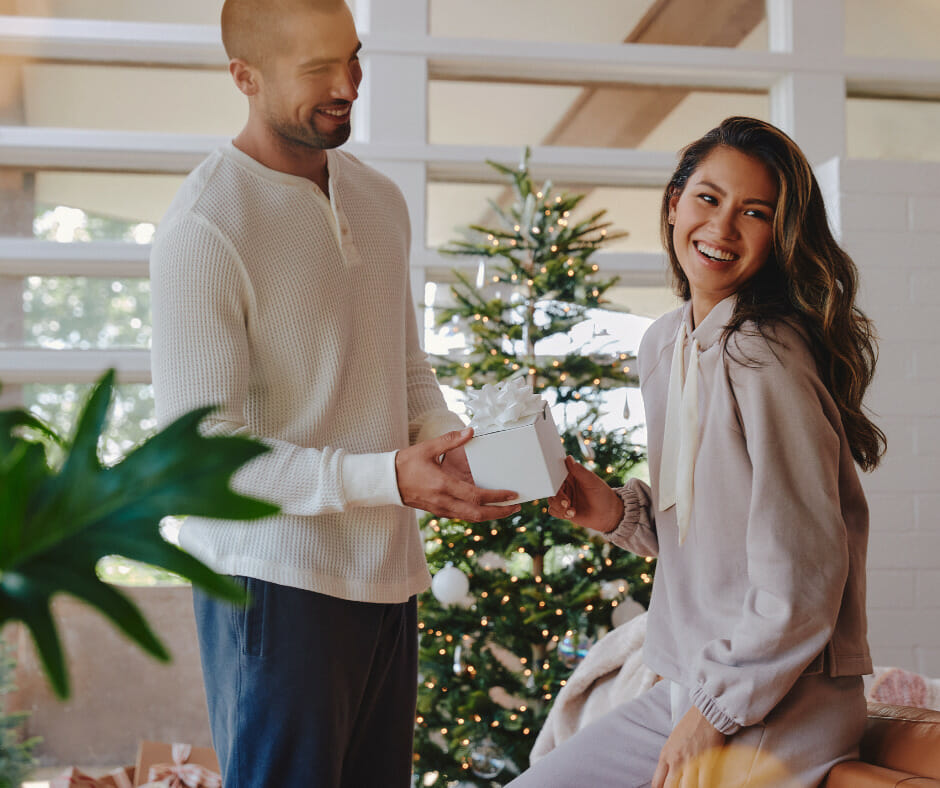 man and woman in pajamas exchanging a gift
