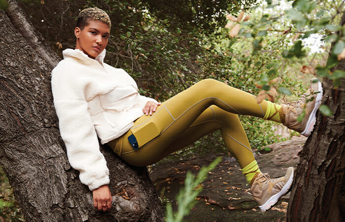 A girl sitting in a tree wearing Fabletics leggings.