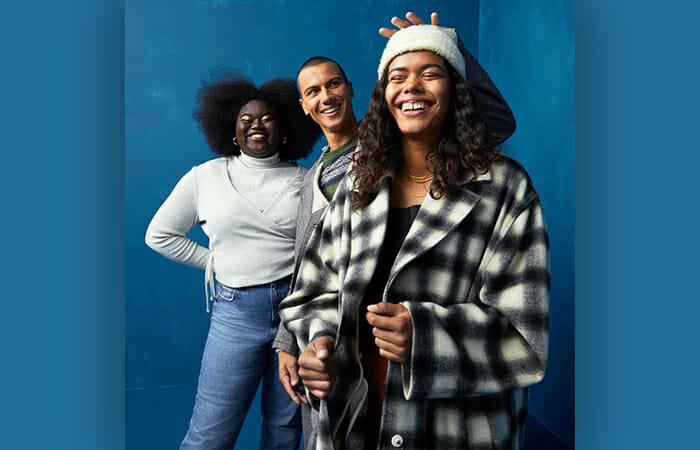 Three people standing against a blue wall laughing and wearing Levi's clothing.