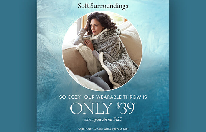 A woman wearing a Soft Surroundings Wearable Throw and promotional copy that reads So Cozy! Our wearable throw is only $39* when you spend $125. *Originally $79.95 while supplies last.