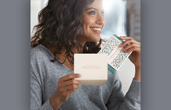 A woman smiling and wearing Soft Surroundings clothes while holding a Soft Surroundings gift card,