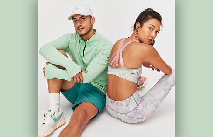 A man and a woman sitting on the ground both wearing Fabletics clothing.