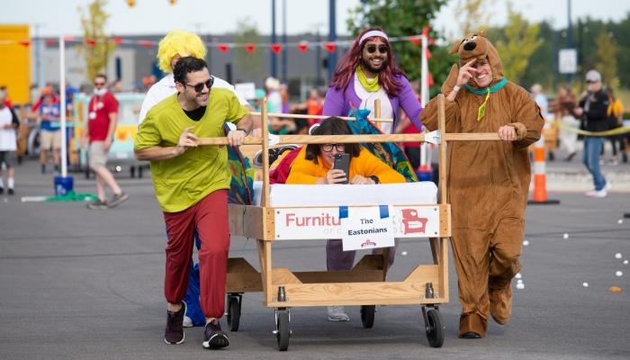 A group of people dressed up as Scooby Doo characters pushing a bed in the bed race.