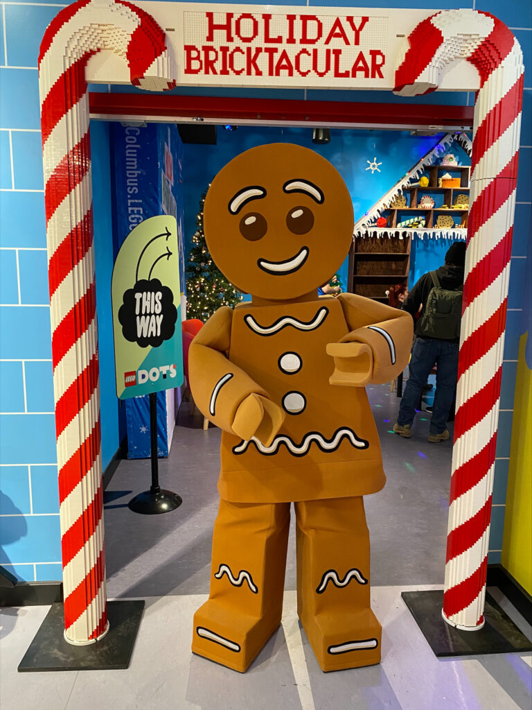 LEGO gingerbread man posing in front of the Holiday Bricktacular.