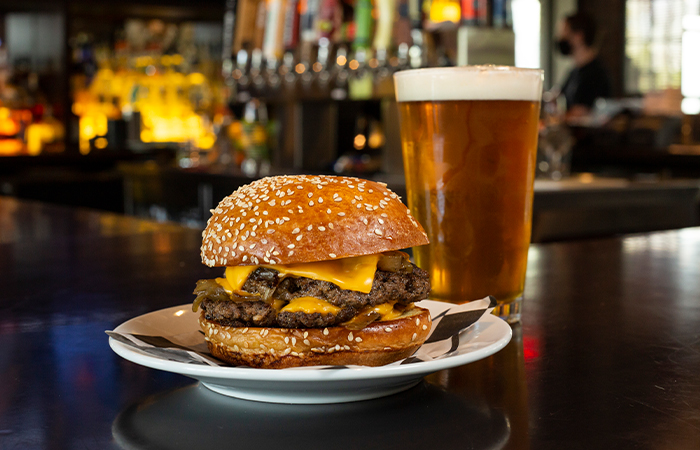 A cheeseburger on a plate and a beer in a glass from Rusty Bucket at Easton Town Center.