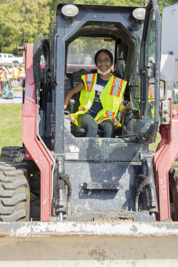 girl scout driving a piece of construction equipment