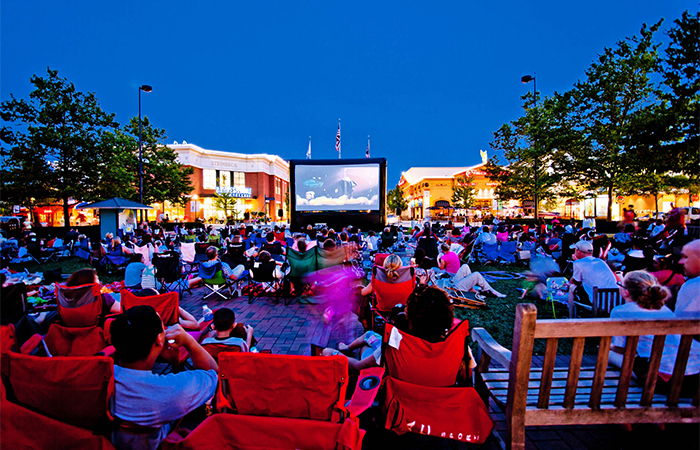 People in chairs on the Town Square at Easton watching a movie.