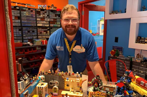 An employee at LEGOLAND standing over some LEGO models.