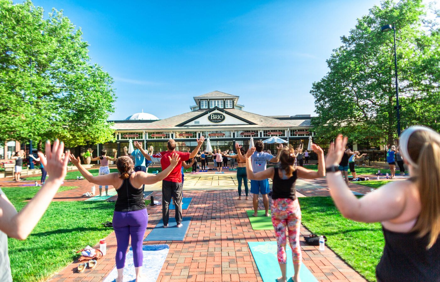 A group of people holding a yoga pose on the Town Square at Easton during Friday morning Yoga on the Square.