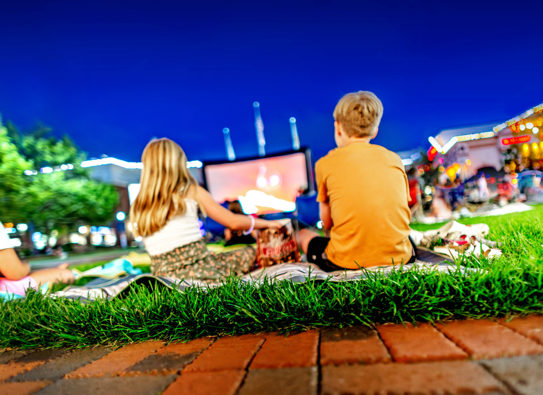 Two kids sitting on a blanket outside watching an outdoor movie at Easton.