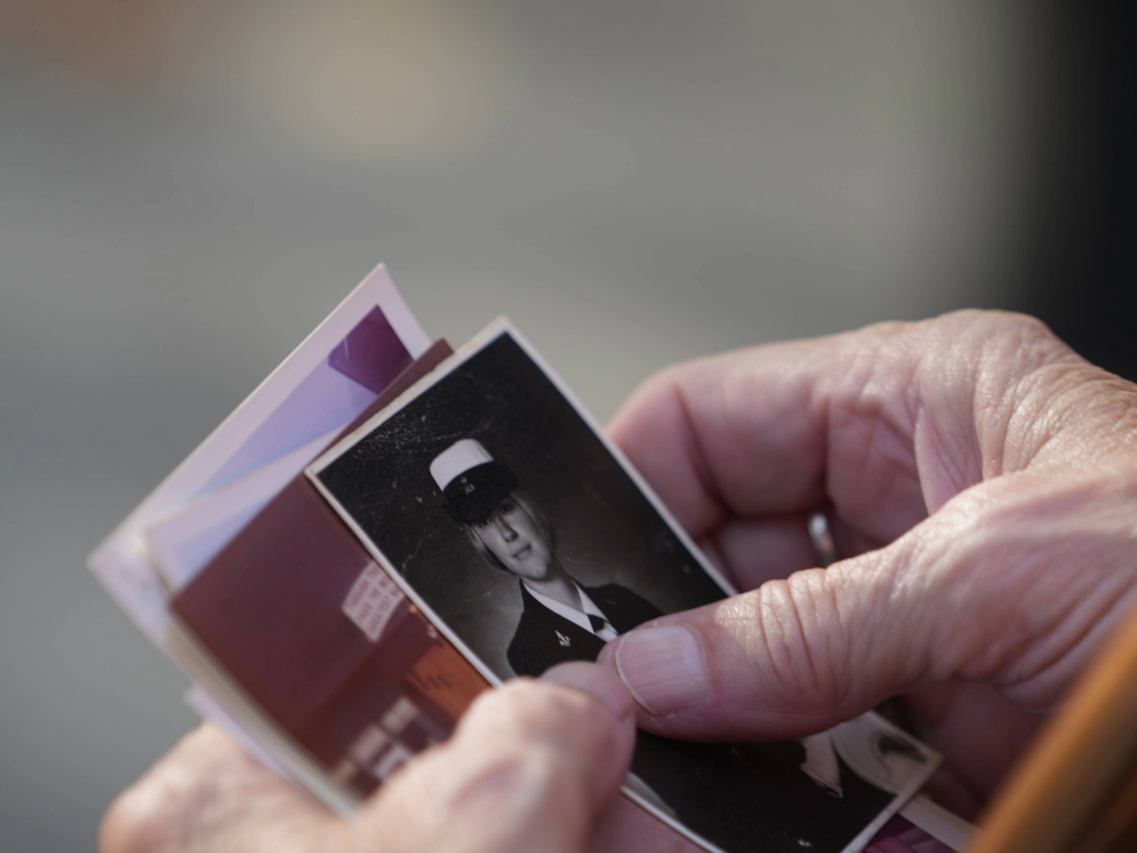 An older person's hand holding historic photos of people that were likely soldiers or medics in a US war.