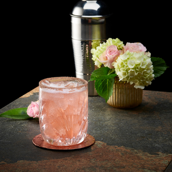 A pink cocktail on a table with flowers in the background at Mastro's.