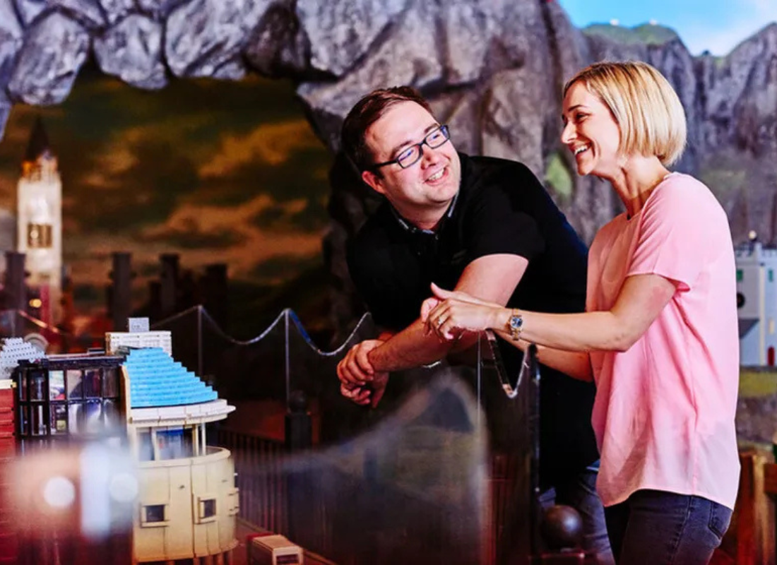 An image of a man and a woman talking and laughing near a LEGO display inside a LEGOLAND Discovery Center.