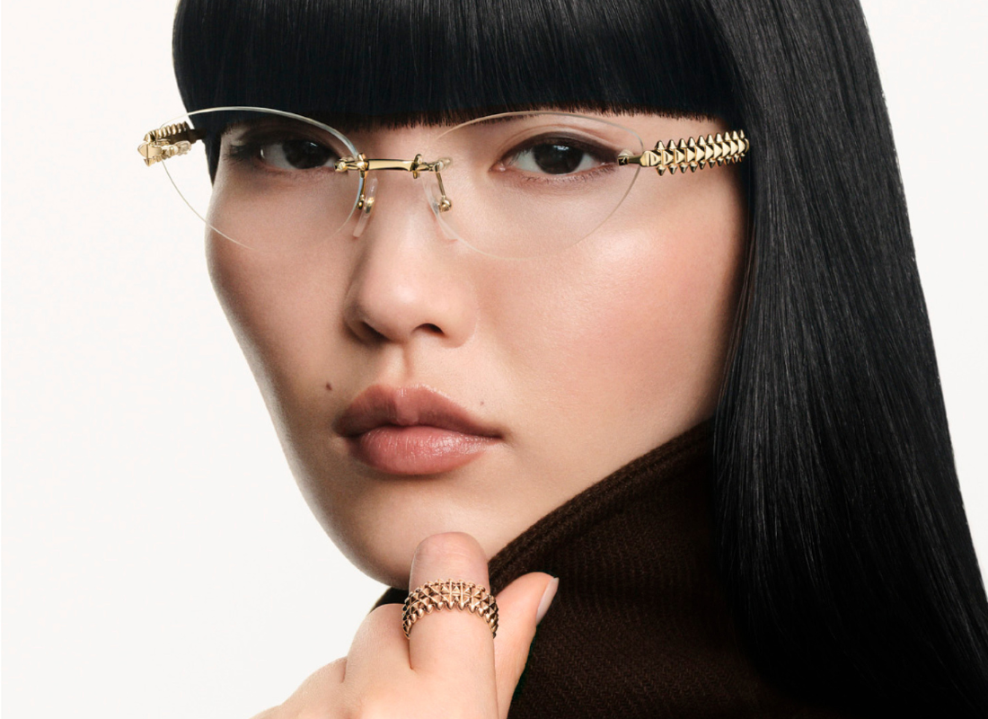 Woman with dark hair wearing gold colored Cartier glasses looking forward