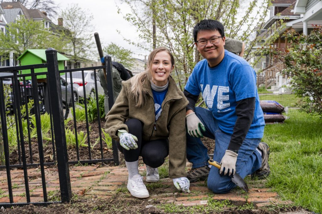 A young female and male wearing gardening gloves repairing a damaged sidewalk outdoors