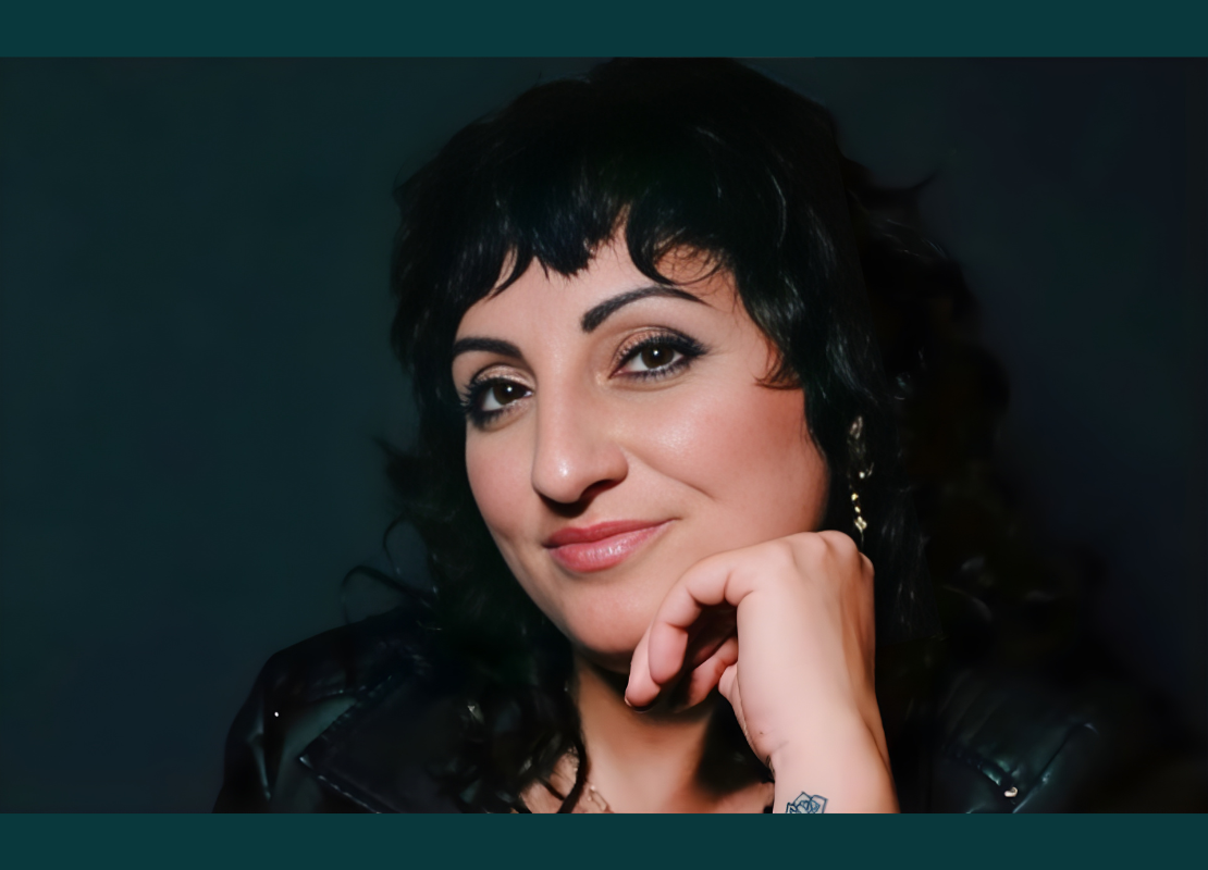 Women with black hair wearing a black leather jacket looking into the camera