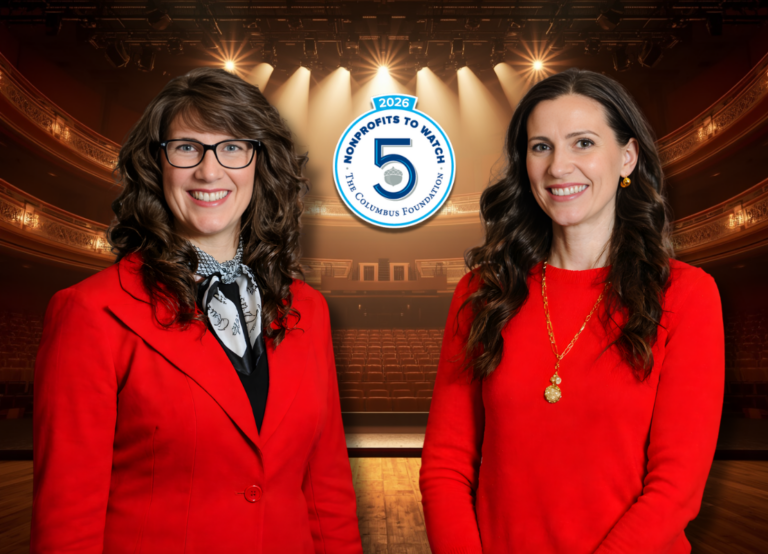 Two women wearing red smiling at the edge of a stage